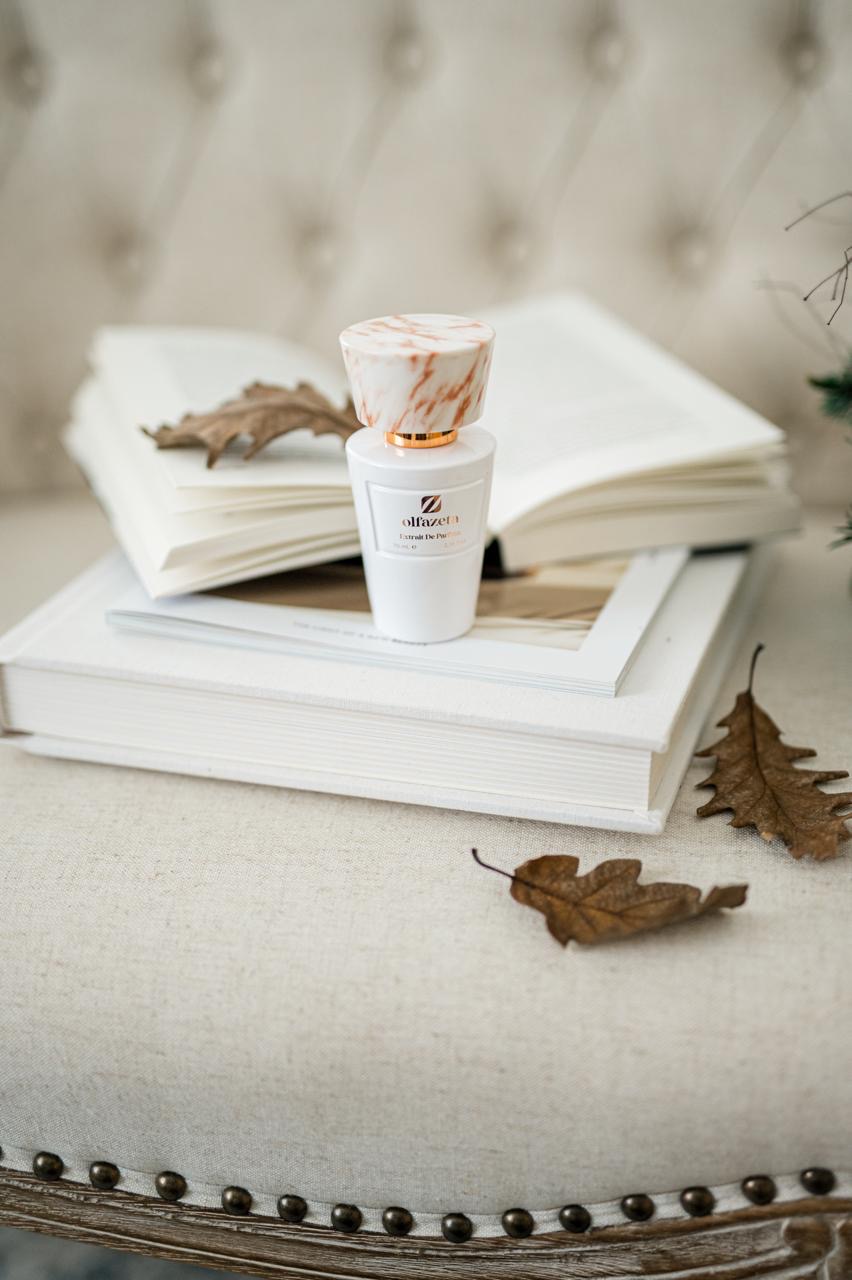 Parfum Olfazeta posé sur livres et feuilles d'automne